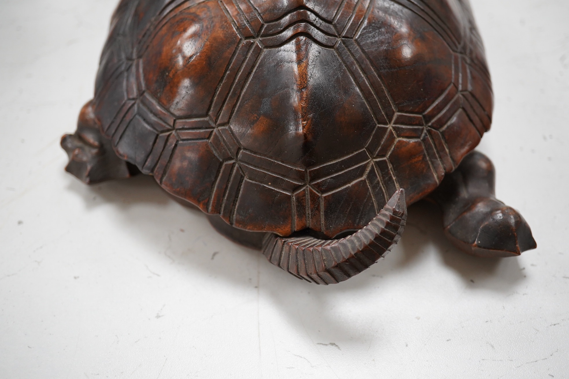 A late 19th century/early 20th century carved walnut box in the form of a tortoise, the shell opening to reveal a compartment, 29cm wide. Condition - fair, tail re-glued